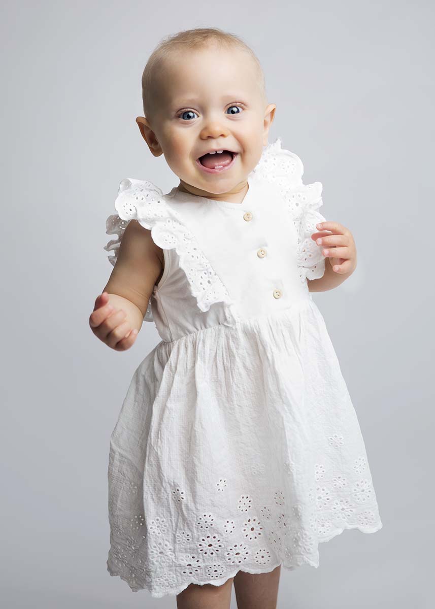 Banrebilde av glad jente med hvit kjole