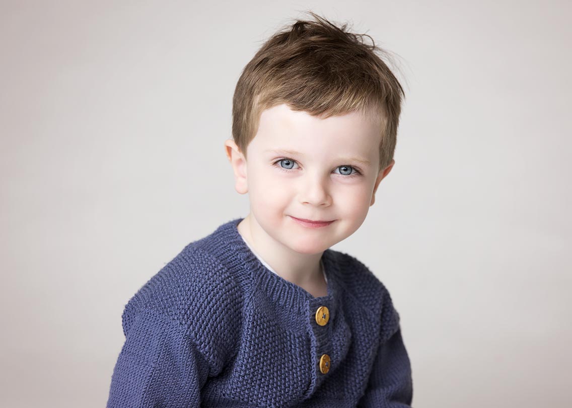 Portrett av en gutt på 6 år, tatt i studio. Gutten ser i kamera og har på blå genser